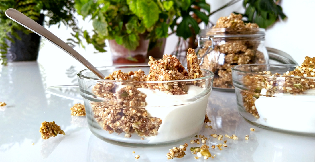 Sinaasappel-kardemomgranola met tijgernotenmeel in een schaaltje met Griekse yoghurt