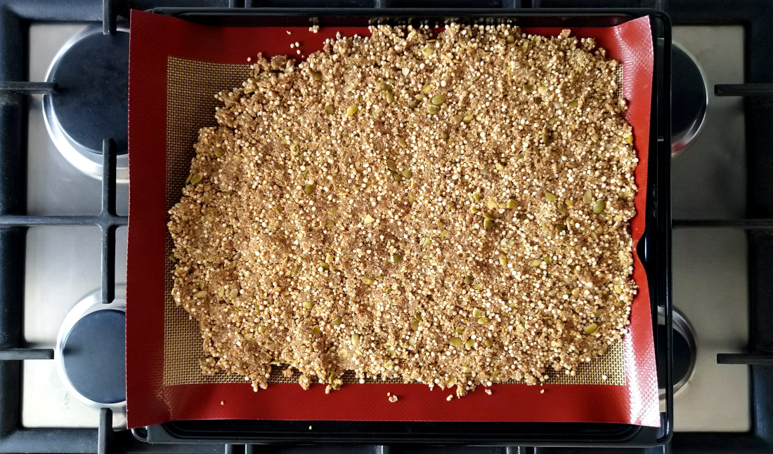 Sinaasappel-kardemomgranola met tijgernotenmeel op een bakplaat