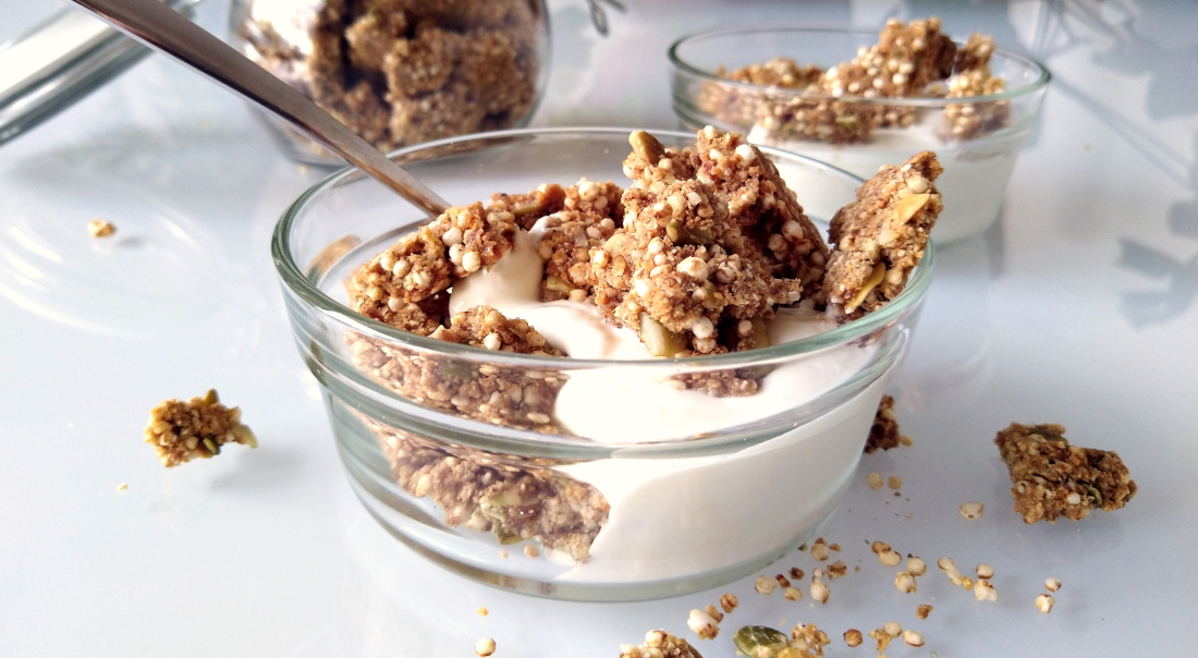 Close-up van Sinaasappel-kardemomgranola met tijgernotenmeel in een schaaltje met Griekse yoghurt