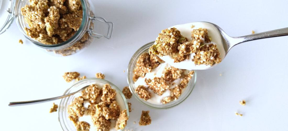 Sinaasappel-kardemomgranola met tijgernotenmeel op een lepel met yoghurt